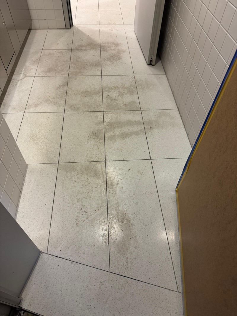Heller Fliesenboden im Sanitärraum mit grauen Ablagerungen vor der Reinigung